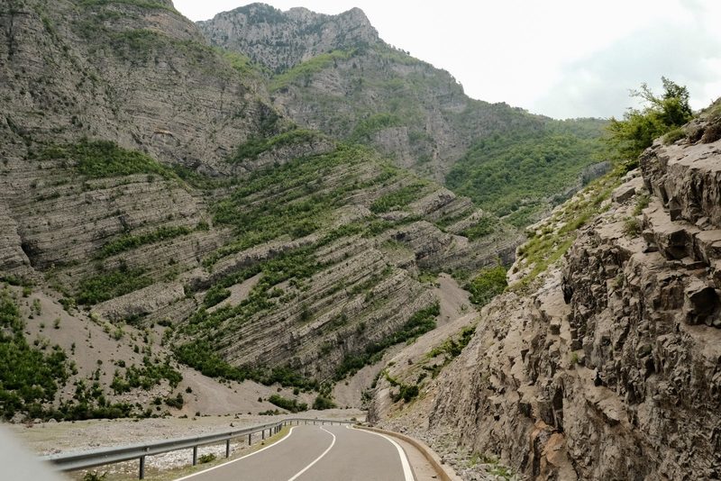 A winding road through a mountainous region with steep cliffs and rocky terrain.